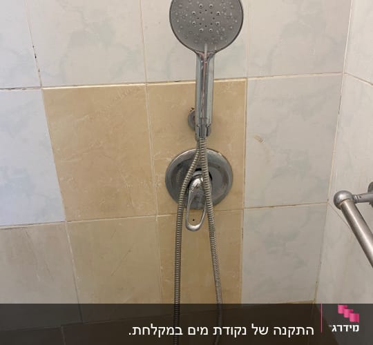 ראש מקלחת על קיר אריחים בחדר אמבטיה